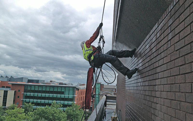 Rope access abseiling from brick building